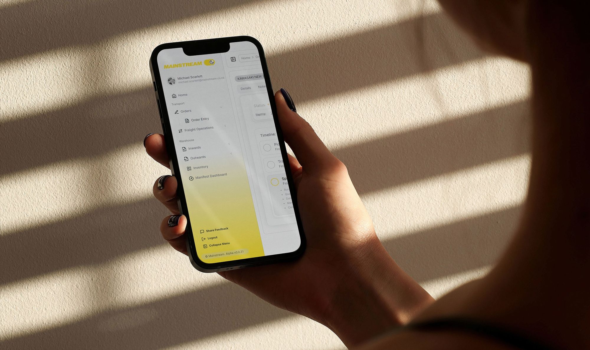 Picture over the shoulder of a woman holding a smartphone looking at Mainstream Edge Portal